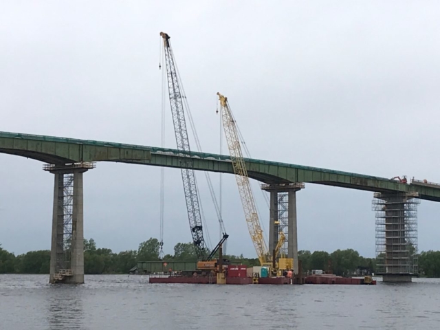 Cranes lowering first girder section on to the barge