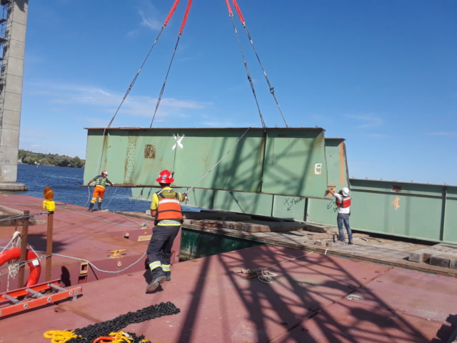 Second piece of removed girder being guided into place on the barge