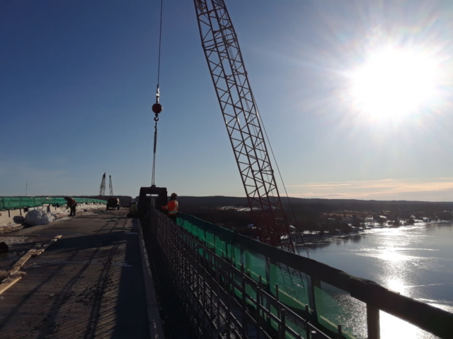 Barrier wall form being lowered into place over top of the rebar