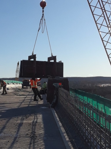 Barrier wall form being lowered onto the deck for placement