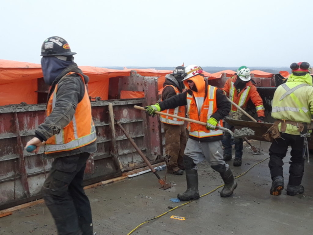 Concrete being topped up in barrier wall forms