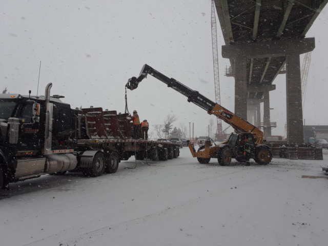 Barrier wall forms being removed from the truck to be lifted by the crane