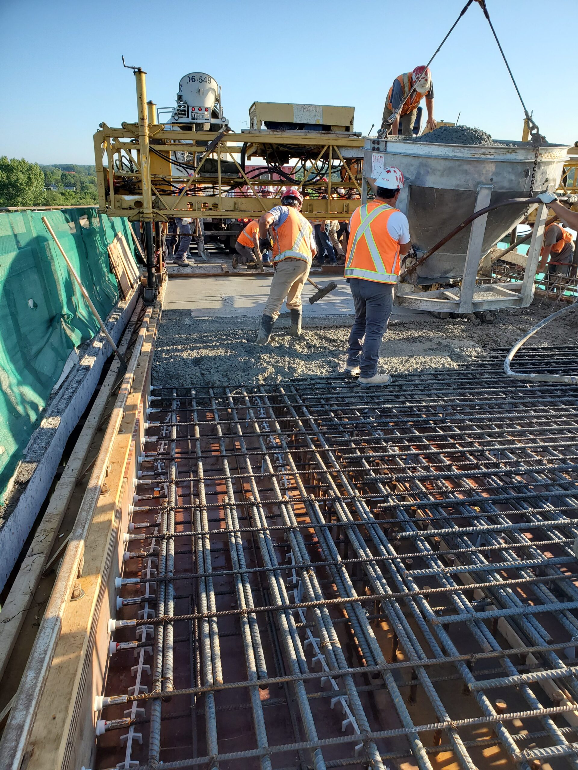 Concrete hopper containing concrete being lowered to the deck