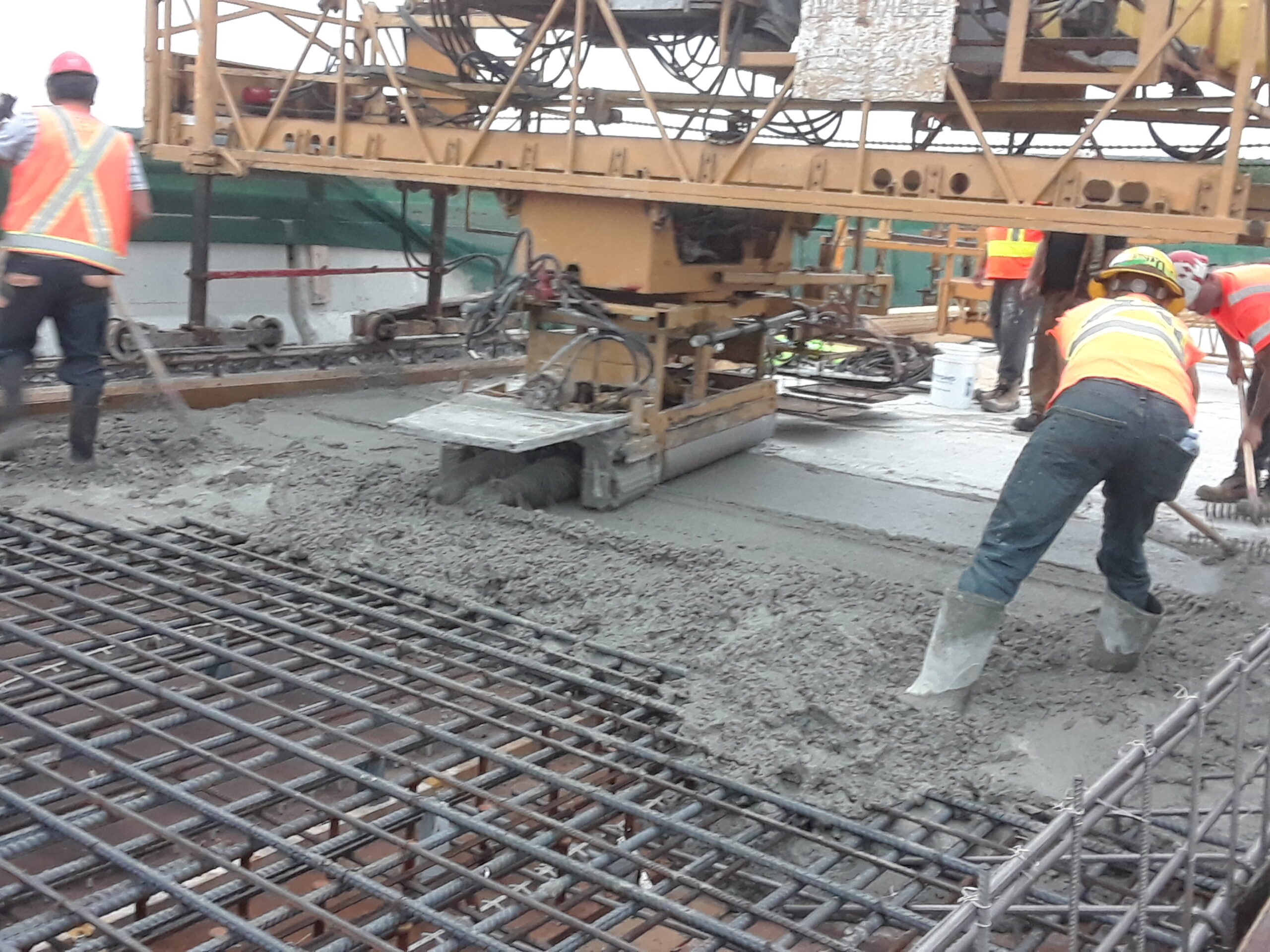 Newly placed concrete being vibrated and spread