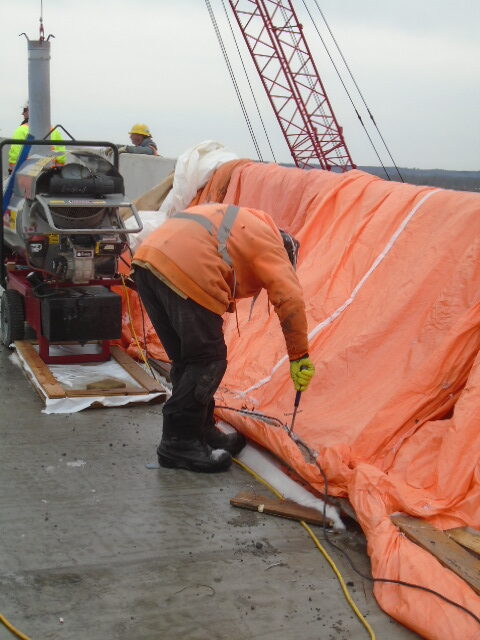 Removing the tarping from the newly placed barrier wall