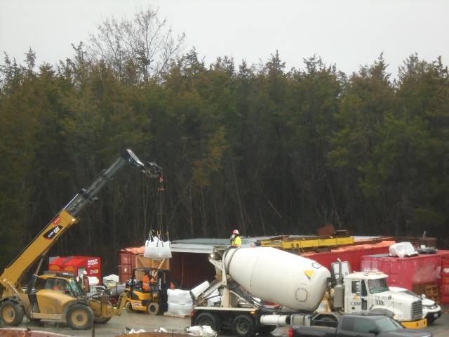 Expanded view of concrete truck and telehandler lifting concrete mix to the truck