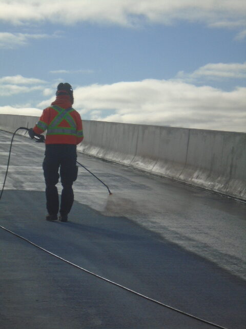 Applying tack coat primer to the concrete deck for waterproofing application