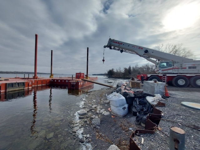 Hydraulic crane placing ramp to access the barge