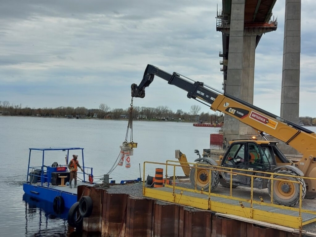 Telehandler loading the buoys on the boat to be placed in the Bay