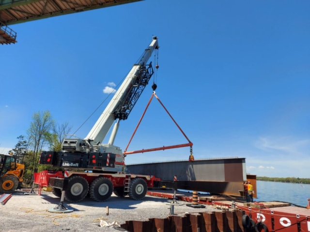 West view of the second approach girder piece being lowered onto the barge