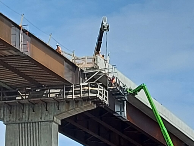 Telehandler lowering the brackets to the man lift for installation