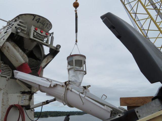 Close-up of concrete truck truck filling the pump truck, 200-ton crane lifting the hopper