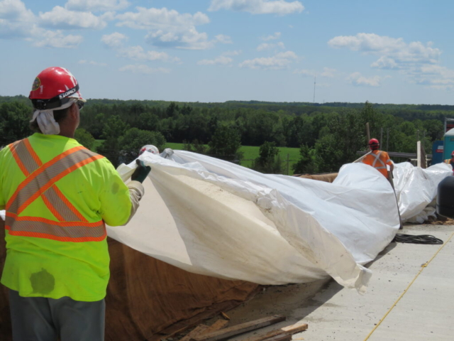 Placing plastic over the wet burlap on the new barrier wall section