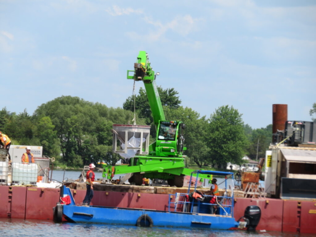 Lifting the hopper of concrete from the boat to the barge