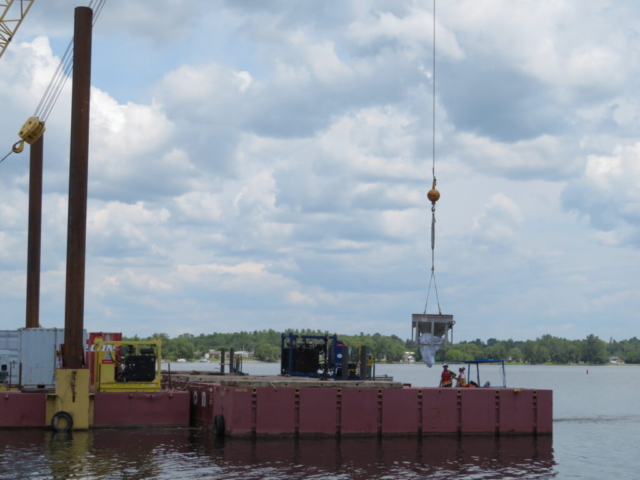 Lowering the hopper to the boat to be taken to the barge for placement