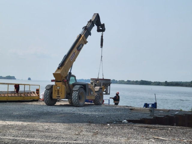 Using the telehandler to lower the concrete hopper onto the boat