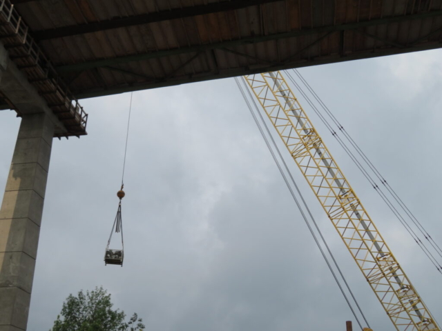 Lower view of containment scaffolding materials being lifted to the bridge deck