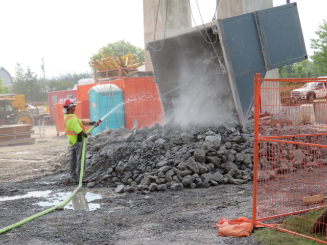 Dumping the containment bin, using water for dust control