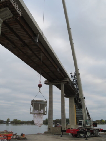 160-ton crane lifting the hopper of concrete to the boat