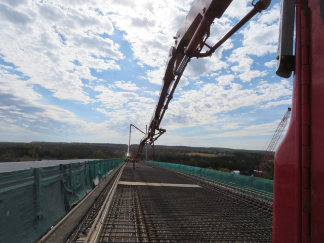 View south, two concrete pump trucks, concrete finisher