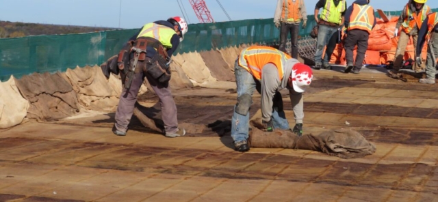 Removing burlap and tarping on the completed section of concrete deck