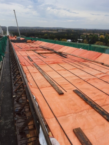 Completed sections of the bridge deck covered with burlap and tarps