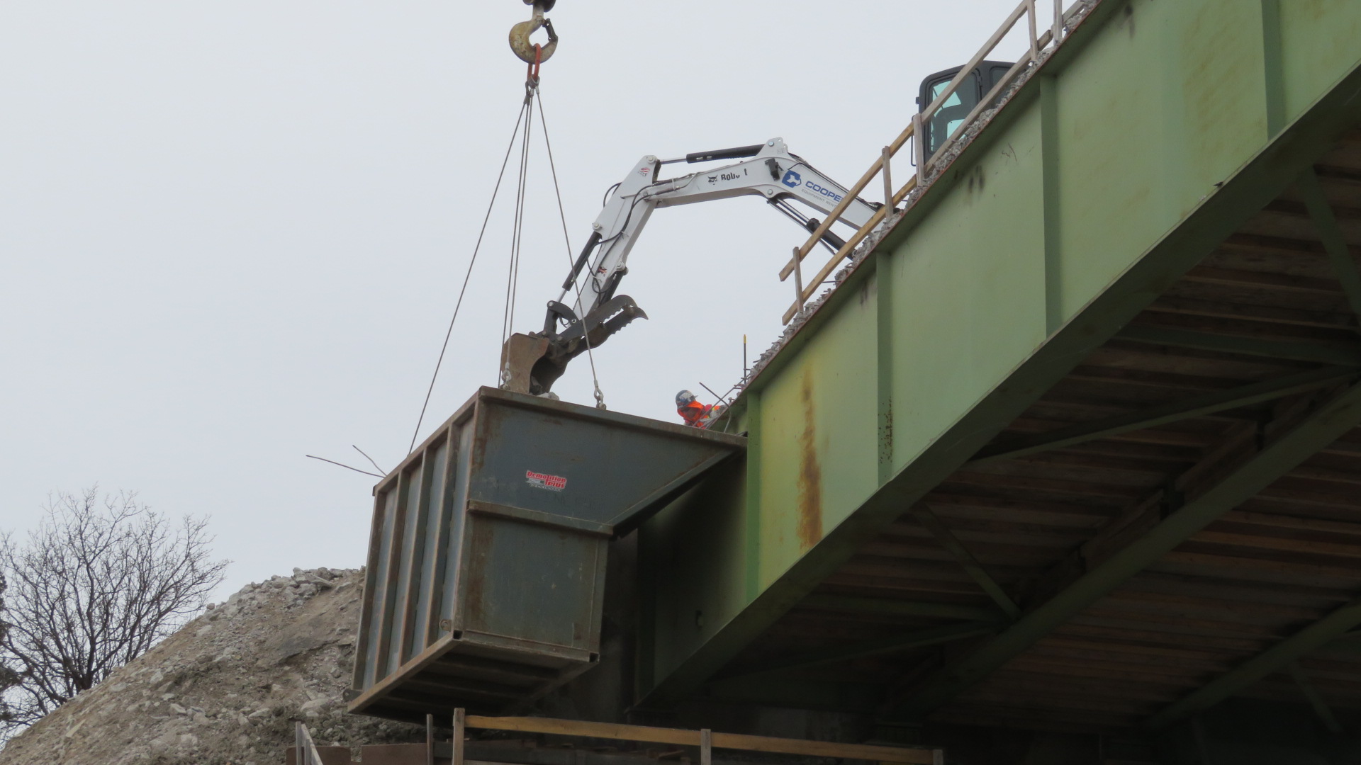 View from below, excavator removing debris into the containment bin