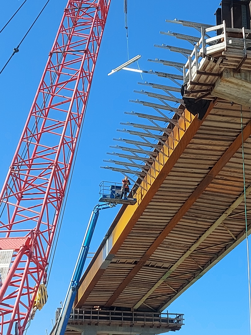 110-ton crane lowering the work platform bracket for installation, using the manlift for installation