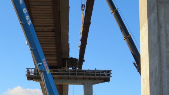View from below of the first girder being lowered into place