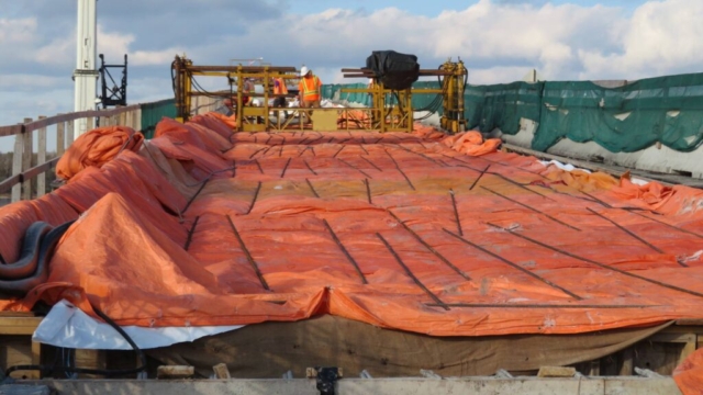 Concrete finisher, placed concrete covered with wet burlap and tarps