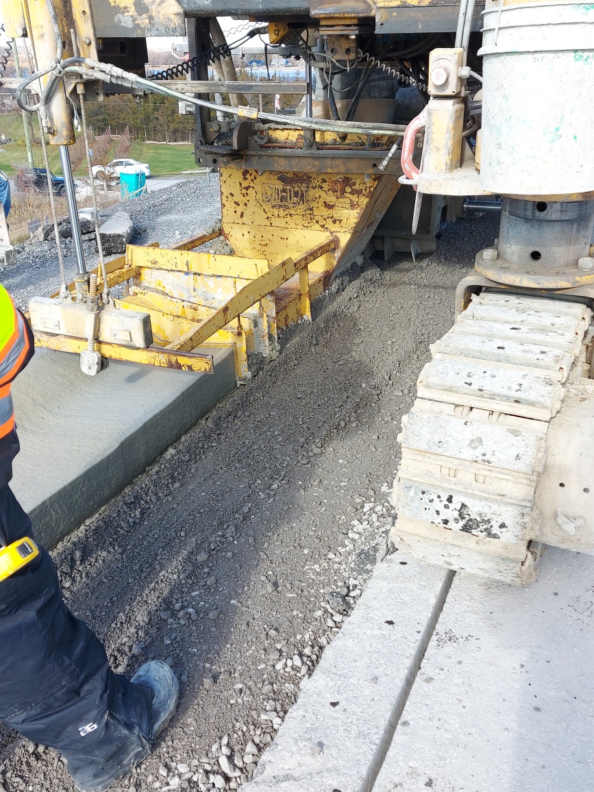 Closeup, slipform machine placing curb and gutter concrete