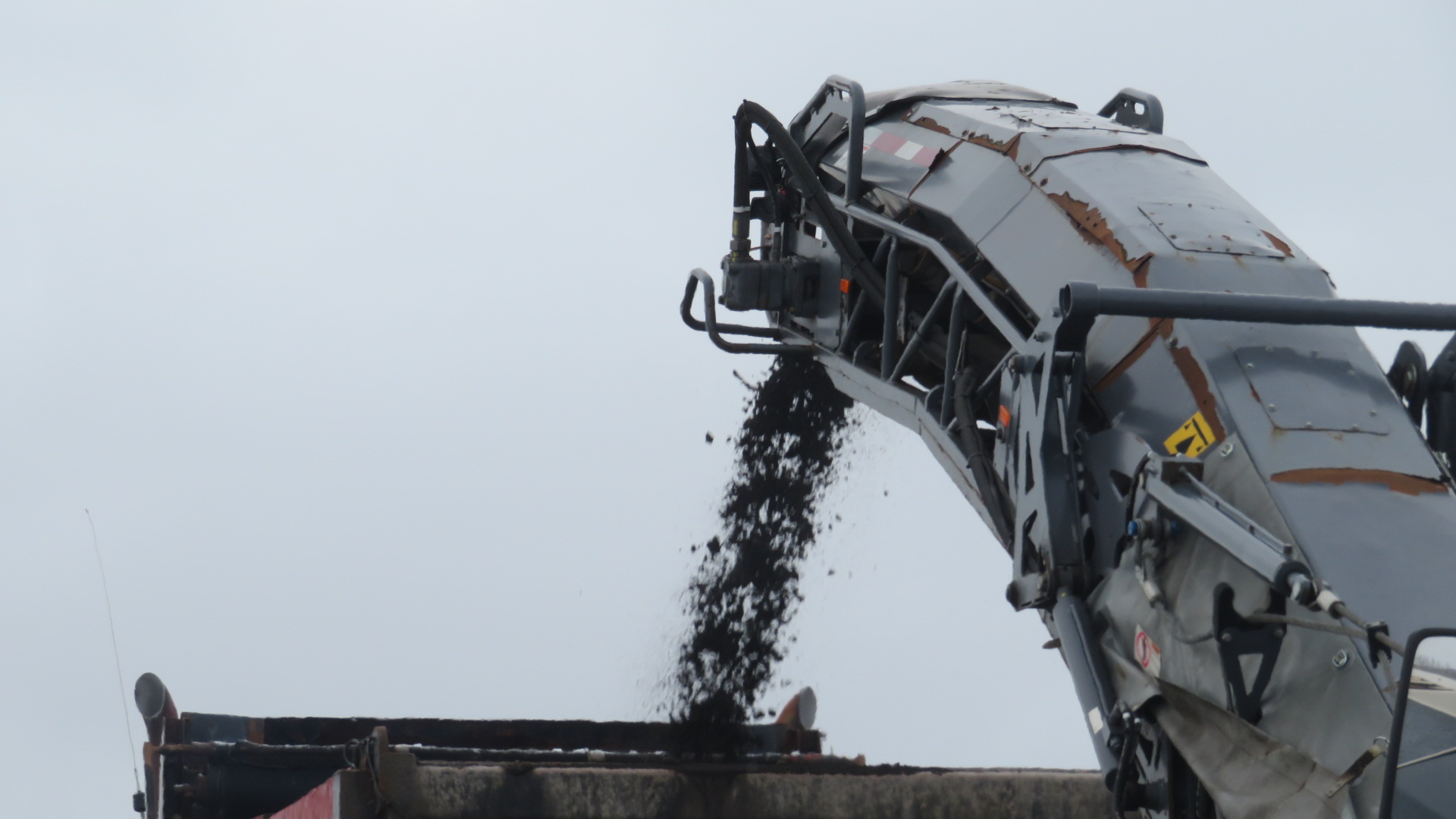 Close-up, milling machine removing asphalt into the truck