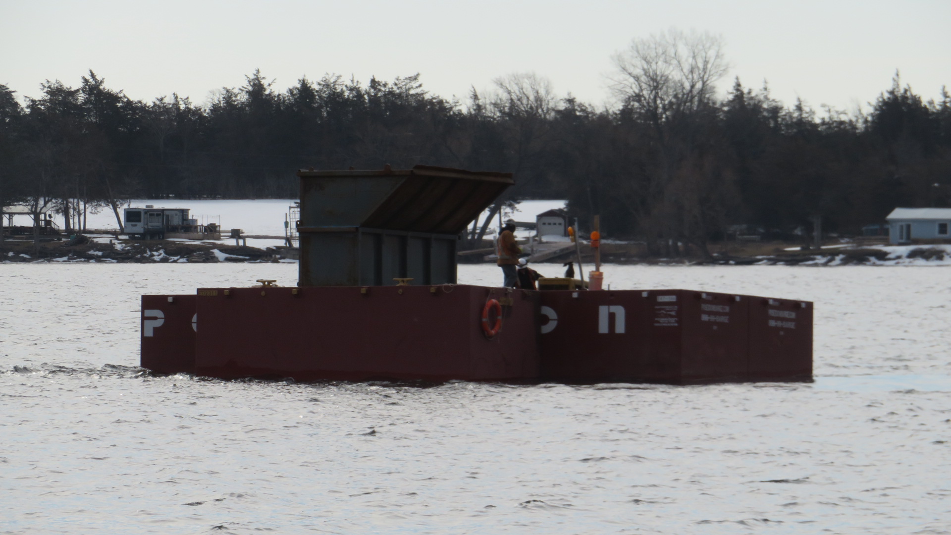 Moving the full containment bin to the shore on the barge