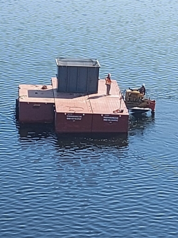 Service barge moving empty bin to the crane barge