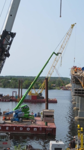 Manlifts and 200-ton crane on barges lifting materials to the bridge deck